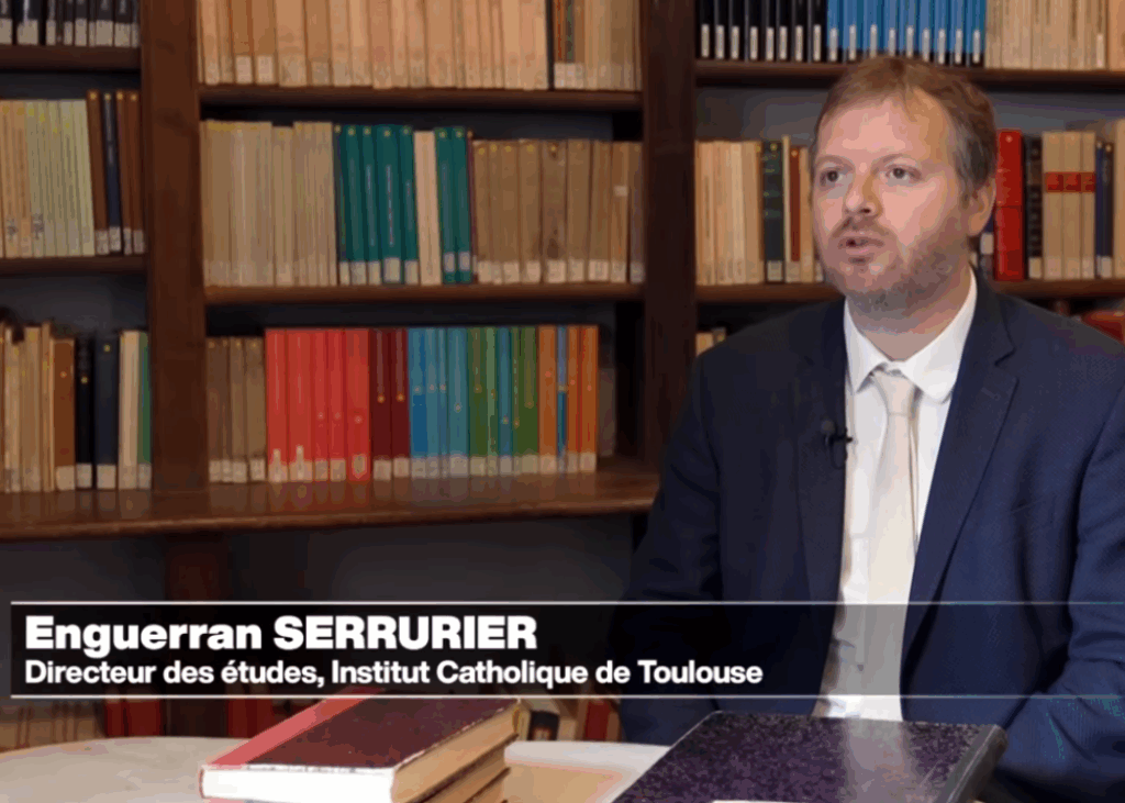 Enguerran Serrurier, directeur des études à l’Institut Catholique de Toulouse, s’exprime dans une bibliothèque, assis à une table avec des livres.